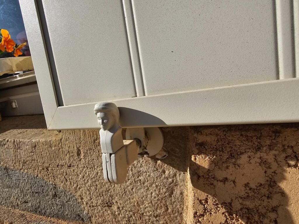 Gros plan sur un arrêt de volet traditionnel de type bergère maintenant un volet alu Ehret à Pierrecourt.
