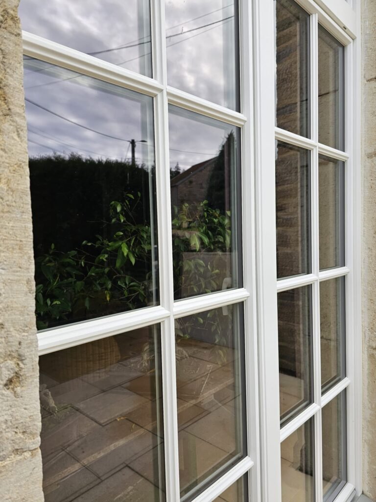 Fenêtres Finstral PVC imitation bois avec petits bois collés sur une maison en pierre Menuiserie Foultot Côte-d'Or