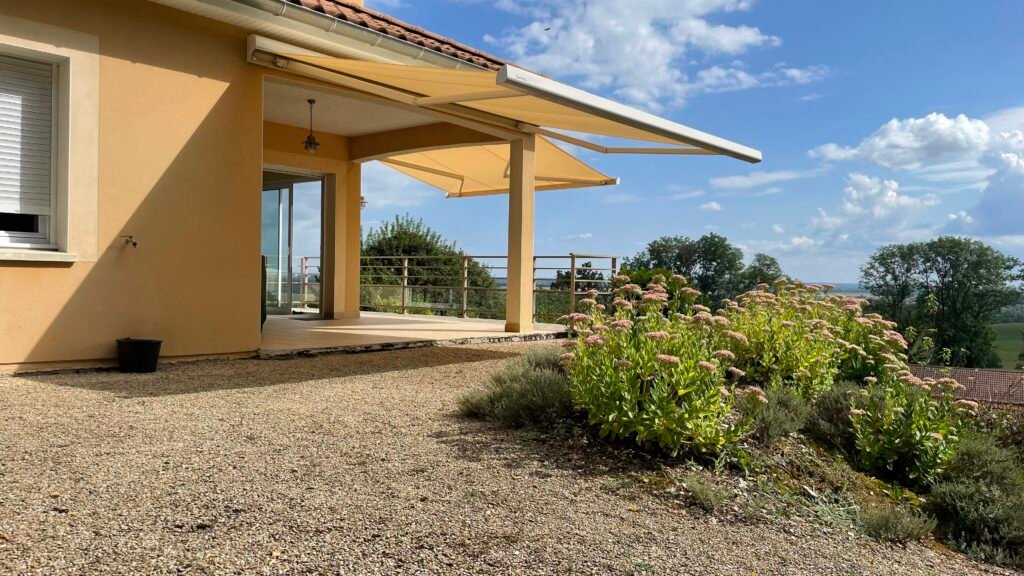 Double store banne coffre beige Brustor B25 déployé sur une terrasse face à une vue panoramique à Euffigneix (52).