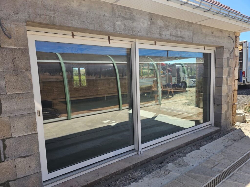 Baies levant-coulissant Finstral posées avec film de protection retiré, vue sur piscine en reflet — Balesmes-sur-Marne, Menuiserie Foultot