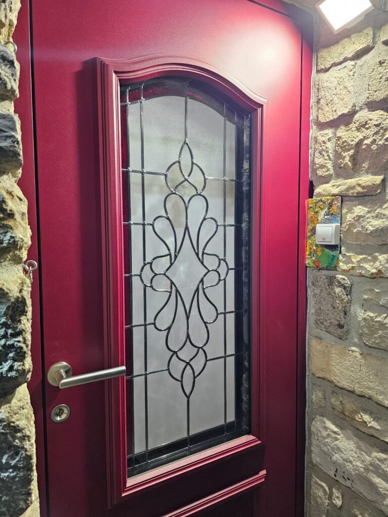 Détail de la poignée et du vitrage décoratif d'une porte d'entrée Inotherm rouge