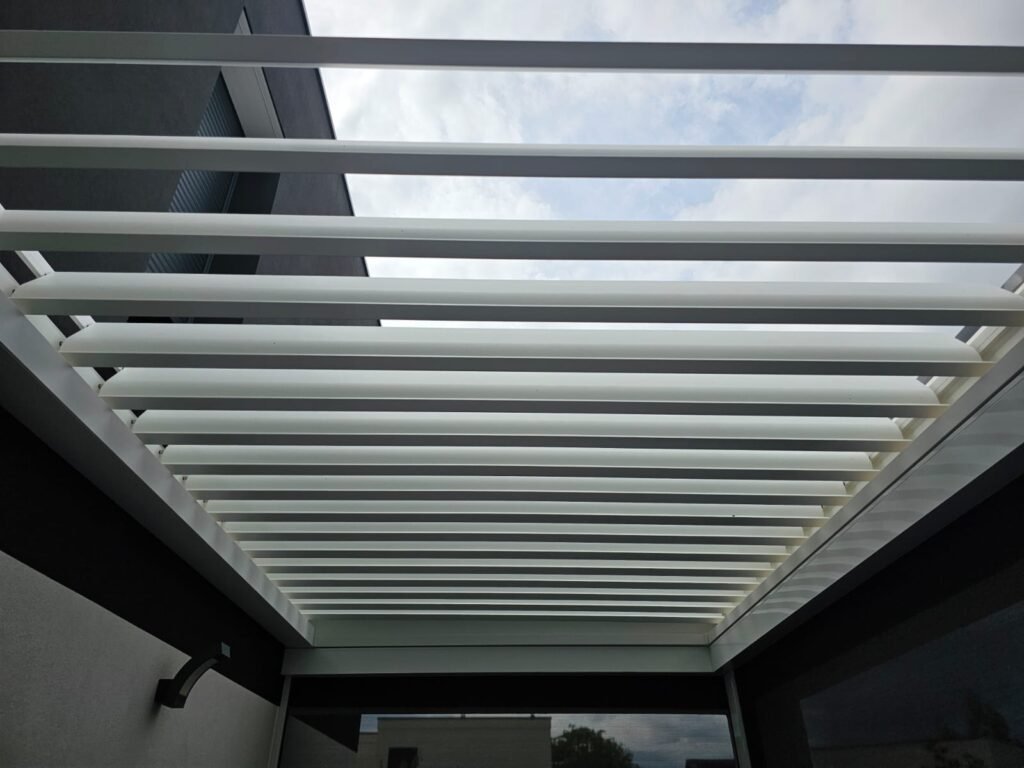 Lames orientables ouvertes d'une pergola bioclimatique laissant passer la lumière du ciel