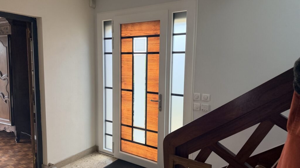 Vue intérieure de la porte d'entrée Inotherm avec vitrages dépolis et fixes latéraux à Leffonds