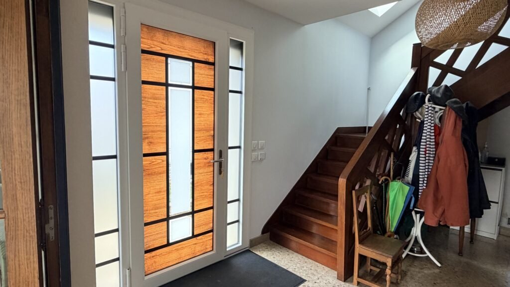 Hall d'entrée et escalier bois éclairés par la porte Inotherm et ses fixes vitrés à Leffonds