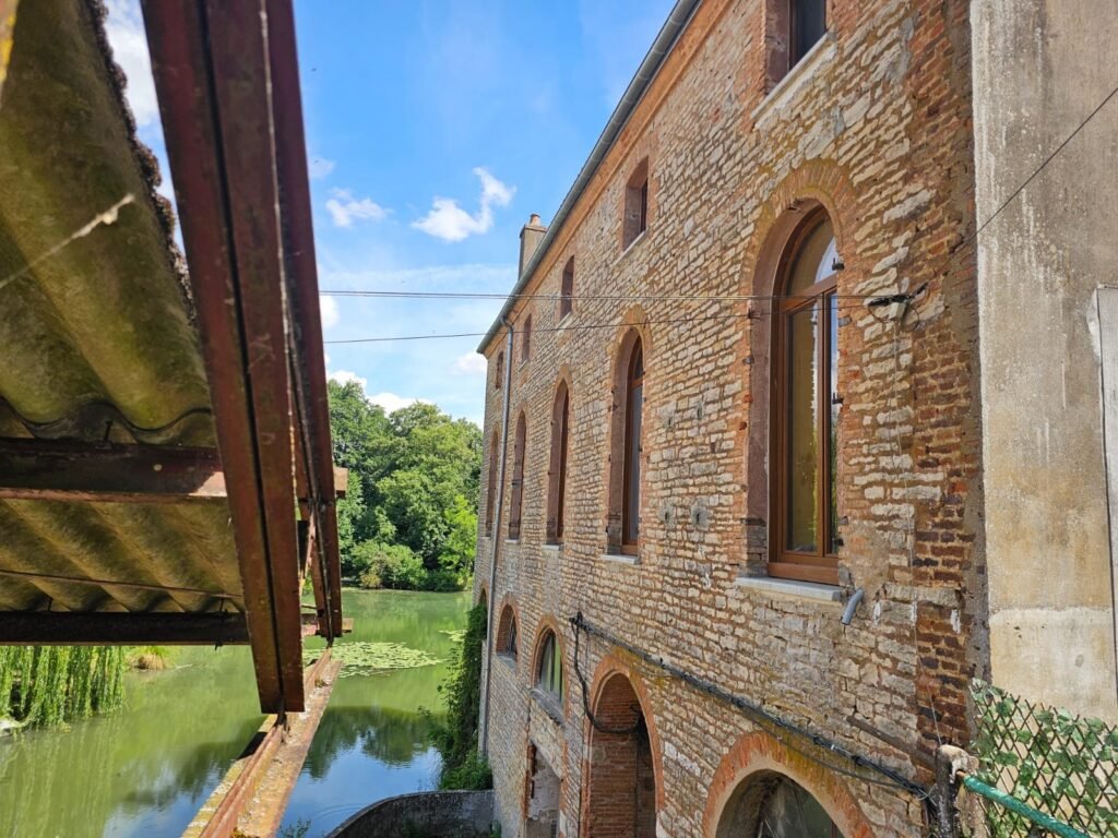 Fenêtres Finstral cintrées teinte chêne sur bâtiment en brique au bord de l'eau à Dijon Menuiserie Foultot