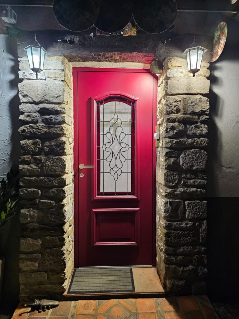 Porte d'entrée Inotherm rouge avec vitrage au plomb, encadrement en pierre à Selongey