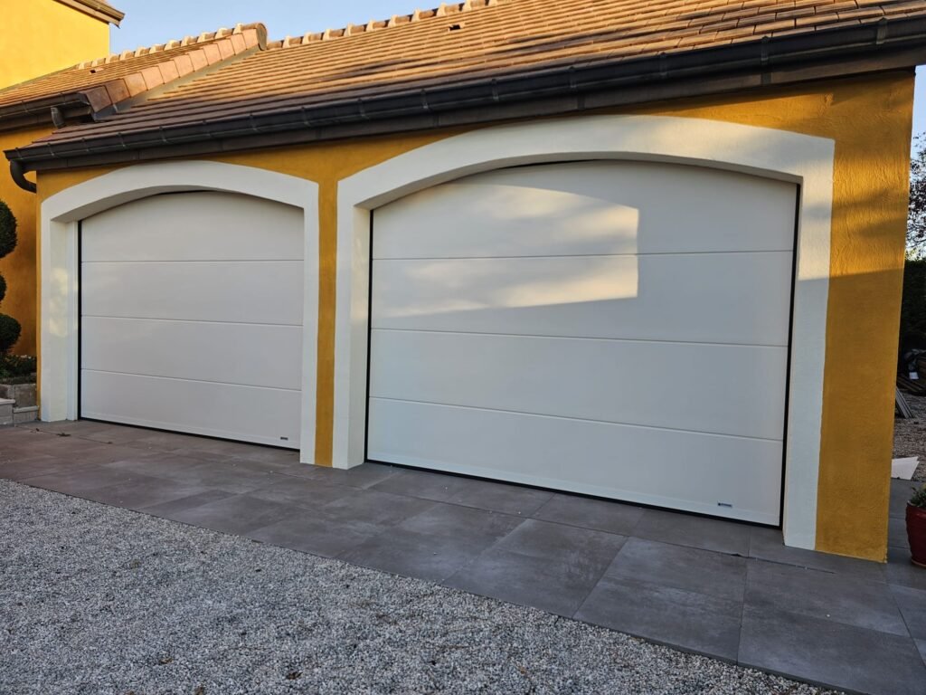 Trois portes de garage sectionnelles Gypass blanc cassé, dont deux sous arc cintré, posées à Rouvres-en-Plaine par Menuiserie Foultot