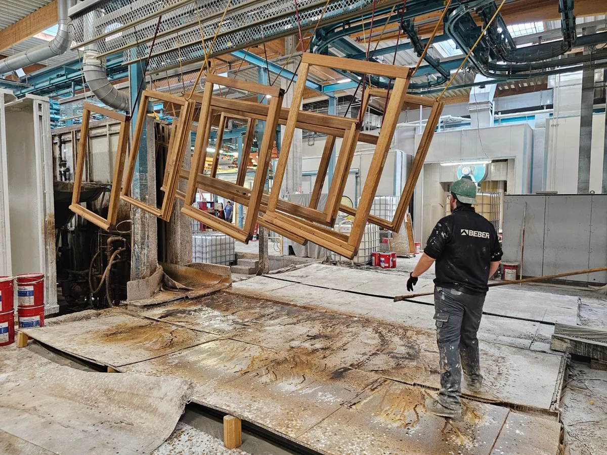 Châssis de fenêtres bois Bieber suspendus à la chaîne de finition de l'usine de Waldhambach, en Alsace, photographiés lors de notre visite