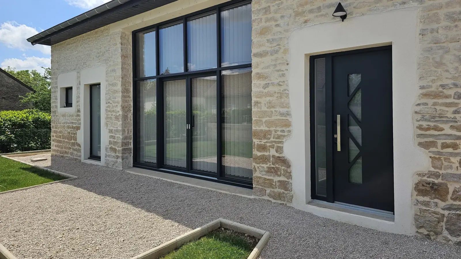 Maison en pierre avec fenêtres et baie en teinte anthracite posées par Menuiserie Foultot