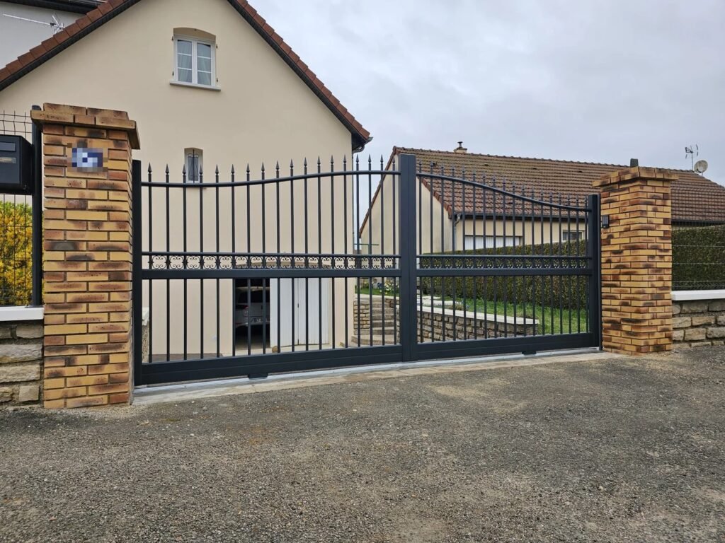 Portail coulissant aluminium Cetal Pléiade RAL 7016 entre piliers en brique, posé à Dommarien par Menuiserie Foultot
