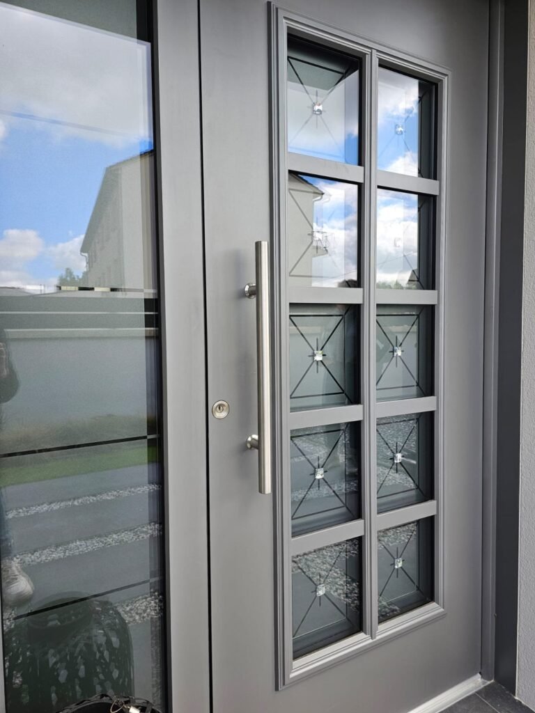 Poignée barre inox brossée sur porte d'entrée Inotherm, vitrage à inserts cristal