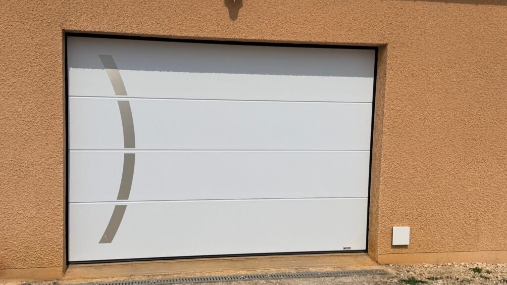 Porte de garage sectionnelle motorisée Gypass blanche avec décor inox courbé installée à Jonchery (52).
