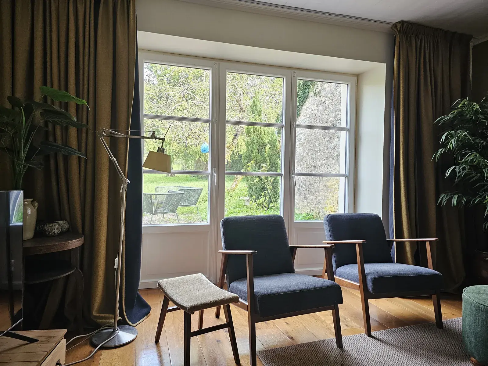 Porte-fenêtre PVC Finstral blanche à petits bois et soubassements moulurés, posée par Menuiserie Foultot dans le salon d'une maison en pierre, vue sur le jardin