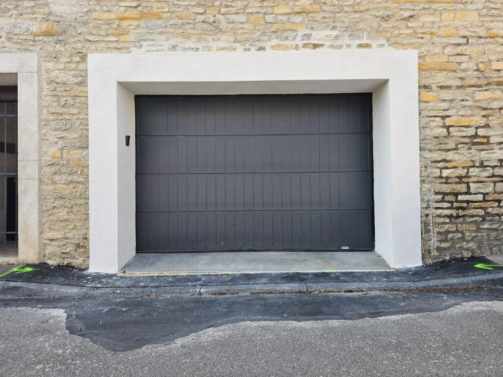 Porte de garage sectionnelle acier Gypass motorisée à nervures verticales, RAL 7021, posée à Corcelles-lès-Monts par Menuiserie Foultot