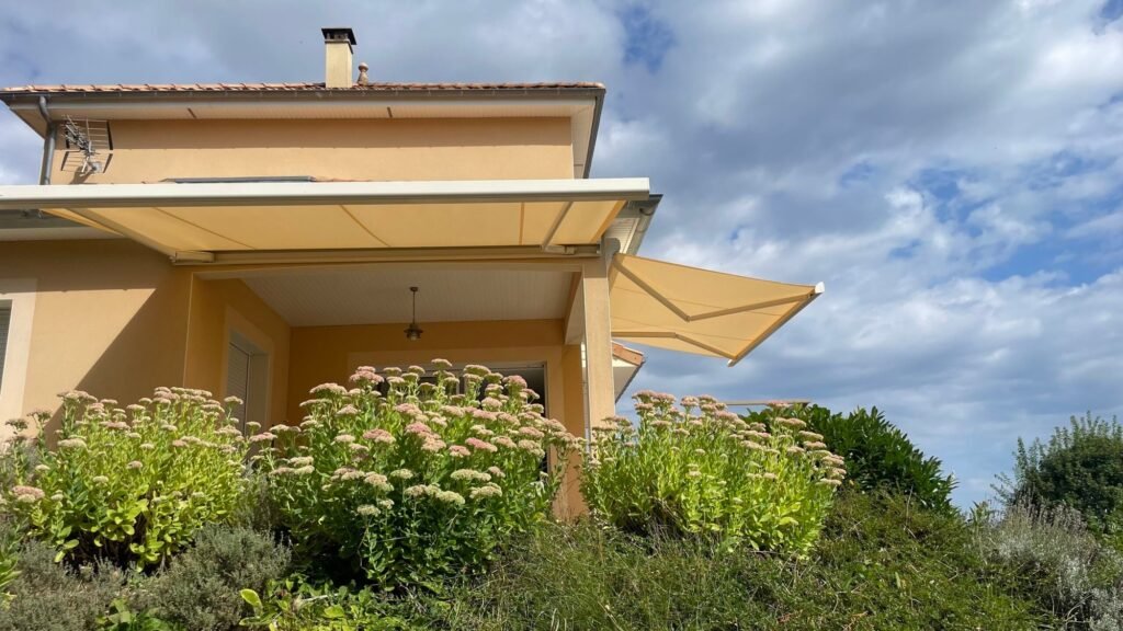 Pose en angle de deux stores bannes à coffre Brustor B25 de couleur beige sur une maison individuelle à Euffigneix (52).