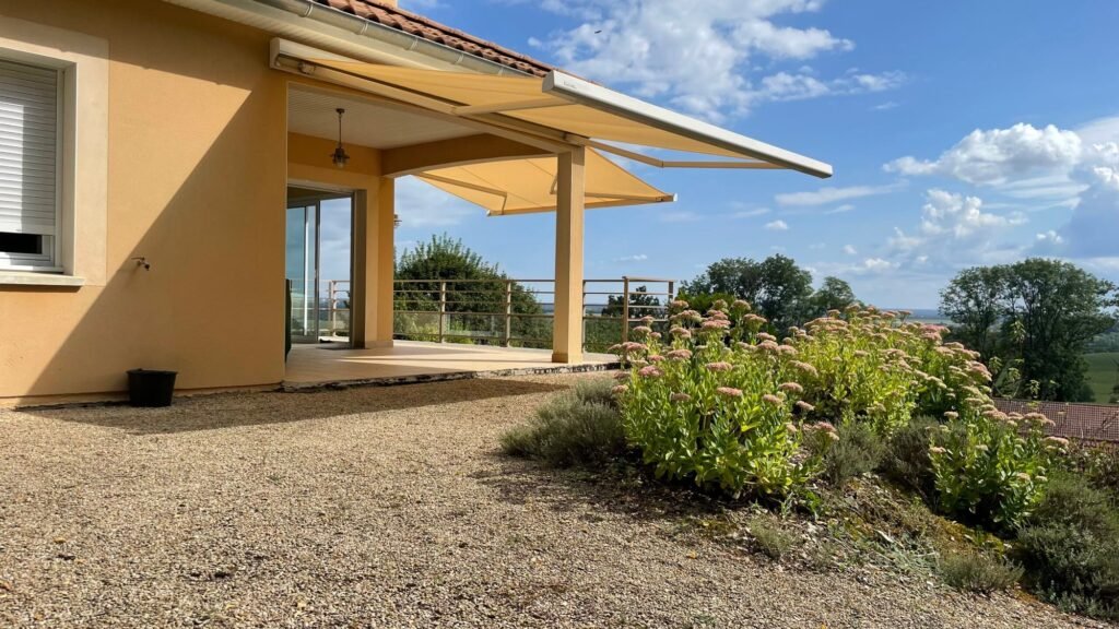 Double store banne coffre beige Brustor B25 déployé sur une terrasse face à une vue panoramique à Euffigneix (52).