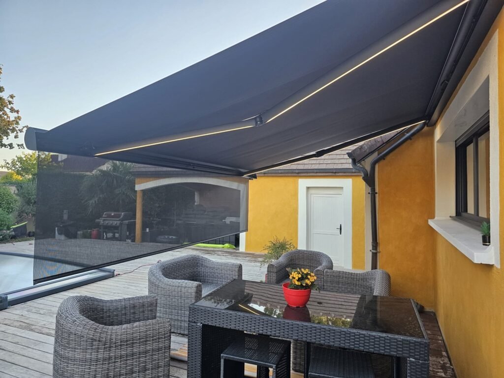 Store banne Brustor B38 Elite déployé, bandeaux LED allumés sous les bras, Rouvres-en-Plaine