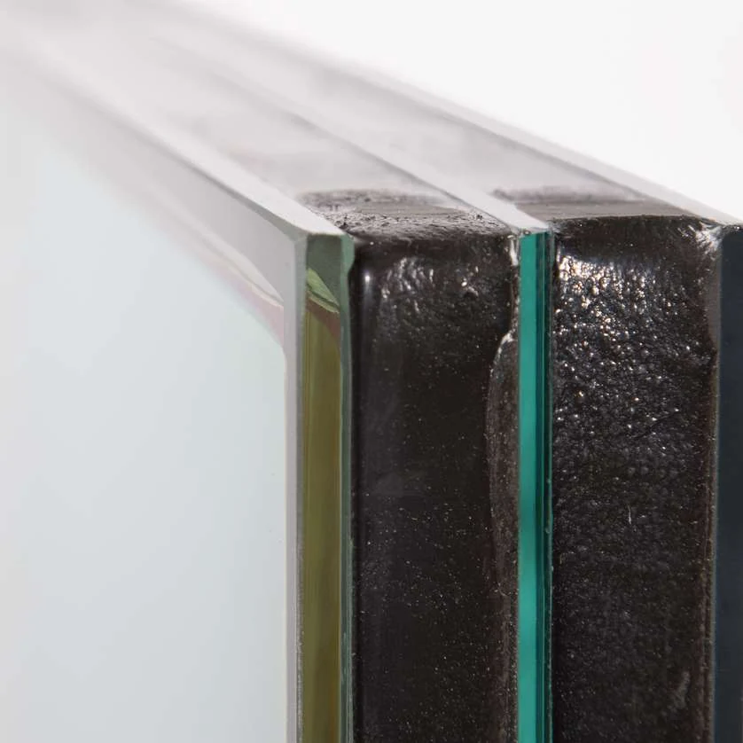 Coupe d'un triple vitrage vu sur la tranche : trois verres, deux lames de gaz et intercalaires noirs isolants (photo Finstral)