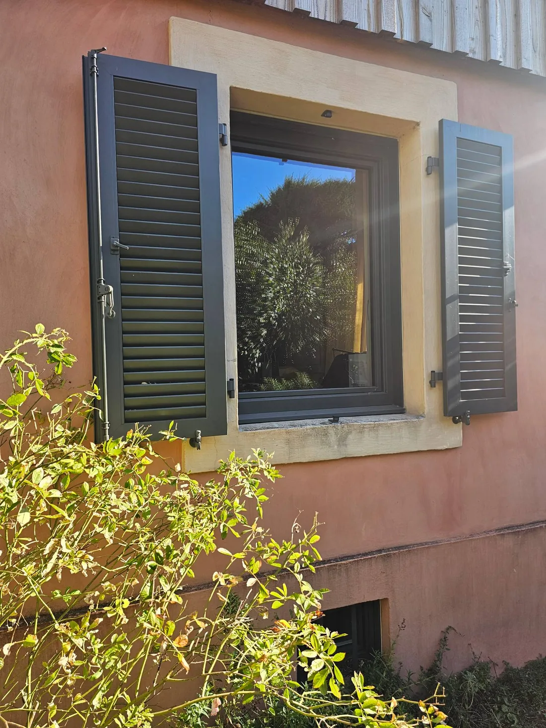 Volet battant aluminium Ehret à lames orientables, teinte anthracite, ouvert de part et d'autre d'une fenêtre sur une façade ocre à Dijon