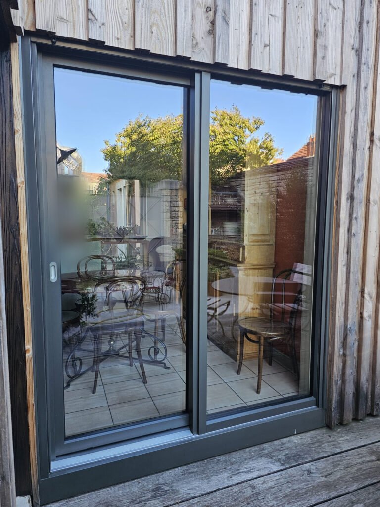 Baie levant-coulissant Finstral aluminium gris RAL 7022 à deux vantaux, sur terrasse en bois, à Dijon