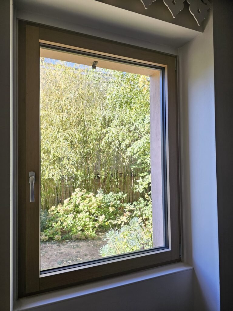 Fenêtre Finstral alu-bois vue de l’intérieur, cadre en bois clair et poignée argentée, à Dijon