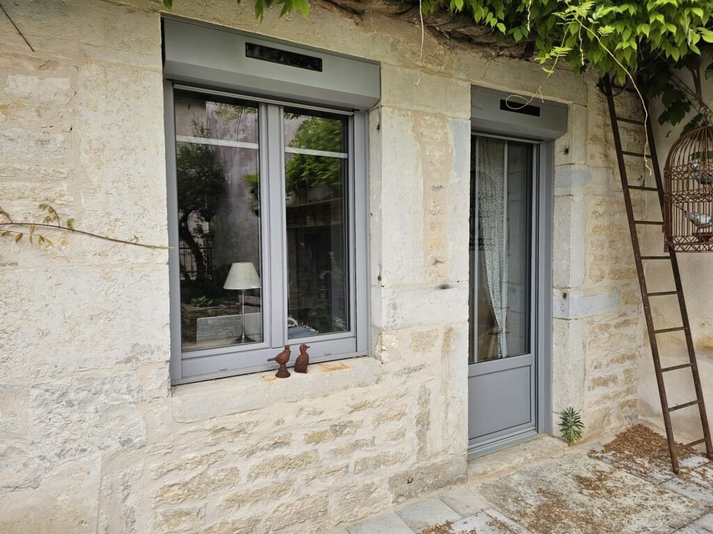 Fenêtre et porte PVC gris Finstral avec volets roulants solaires Roma, mur en pierre à Fontaine-Française