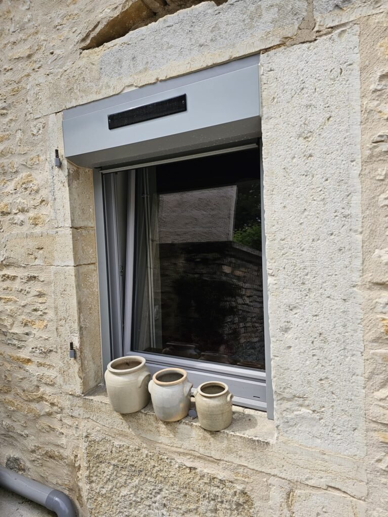 Volet roulant solaire Roma avec coffre gris et panneau solaire, fenêtre PVC Finstral ouverte en oscillo-battant
