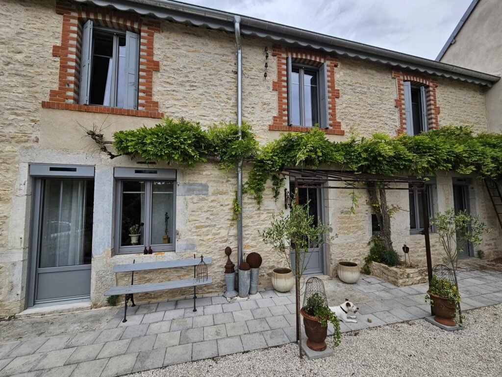 Façade en pierre avec fenêtres et portes PVC gris Finstral, volets roulants solaires Roma et glycine à Fontaine-Française