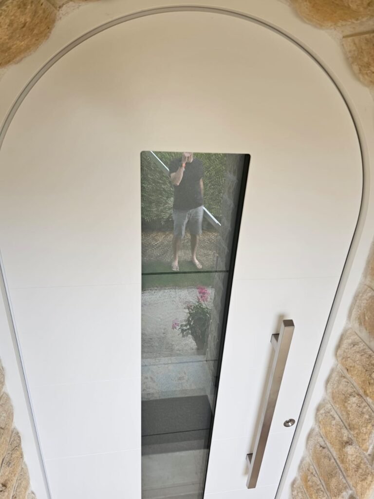 Haut de la porte d'entrée cintrée Inotherm et son cadre fin épousant l'arc de pierre, Orgeux