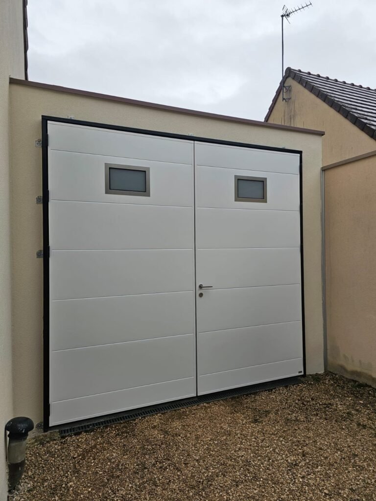 Vue de côté de la porte de garage battante Moos blanche, vantail principal avec poignée et deux hublots