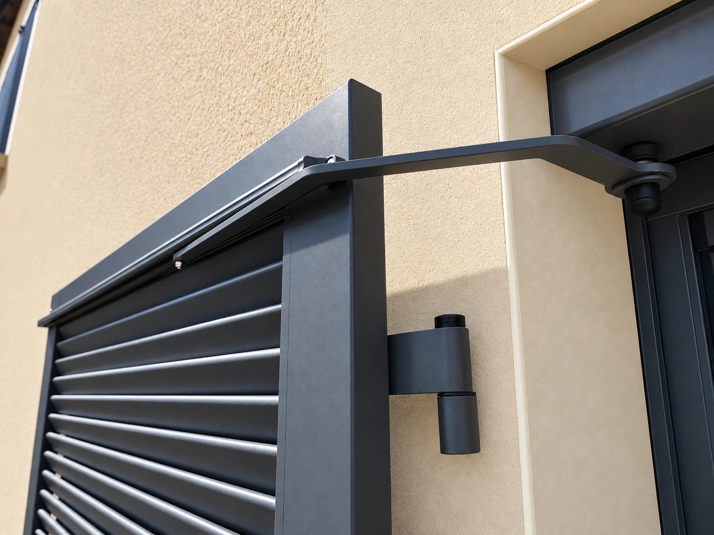 Bras de motorisation et gond d'un volet battant aluminium à persiennes gris anthracite à Verbiesles, en Haute-Marne