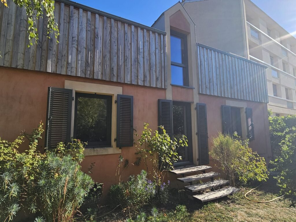Façade enduit ocre rose avec volets battants aluminium Ehret à lames orientables gris RAL 7022 et fenêtres Finstral, à Dijon